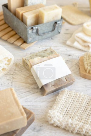 Photo for Organic handmade beige soap bar with blank label on soap saver bag near hygiene Items - natural sponges and brush, bamboo toothbrushes and cotton swabs, close up,  mockup - Royalty Free Image