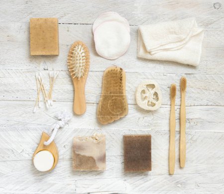 Photo for Soap bars and natural hygiene Items top view on white wooden table. Towel, natural sponges and brush, bamboo toothbrushes and cotton swabs, top view - Royalty Free Image