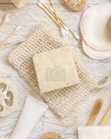 Photo for Organic handmade beige soap bars on soap saver bag near hygiene Items - natural sponges, bamboo toothbrushes and cotton swabs top view. Natural herbal products facecare - Royalty Free Image