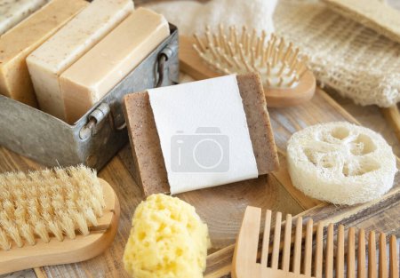 Photo for Organic handmade beige soap bar with blank label on soap saver bag near hygiene Items - natural sponges and brush, bamboo toothbrushes and cotton swabs, close up,  mockup - Royalty Free Image
