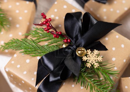 Téléchargez les photos : Cadeau enveloppé avec arc noir, décor de Noël et branches de sapin vert fermer. Noël ou Nouvel An Fscene atmosphérique de vacances avec des boîtes-cadeaux décorées - en image libre de droit