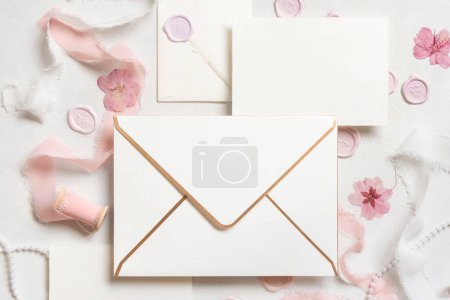 Photo for Envelope and card near pink decorations, seals and silk ribbons on white table top view,  wedding mockup. Romantic scene with horizontal blank card flat lay. Valentines, Spring or Mothers day concept - Royalty Free Image