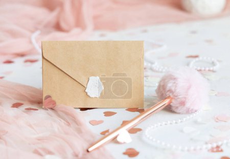 Photo for Sealed envelope near pink decorations, hearts and silk ribbons on white table close up. Romantic mockup for Wedding, Valentines, Spring or Mothers day stationery - Royalty Free Image