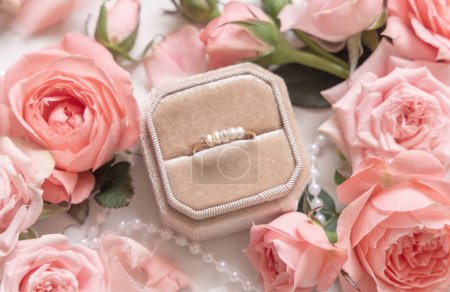 Photo for Engagement ring in a box between light pink roses and buds close up,  romantic wedding preparations. Marriage proposal concept, valentines day scen - Royalty Free Image