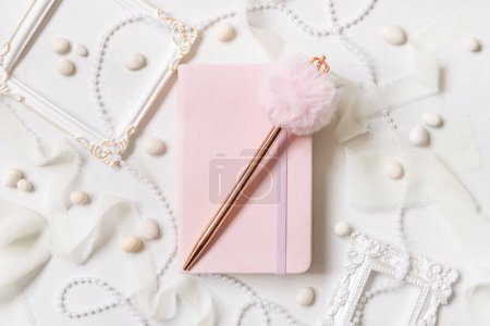 Photo for Pink school notebook, decorative gemstone pen and romantic decor on white top view. Textbook mockup. Dairy cover with place fot text. Valentines, educational and girly concept - Royalty Free Image