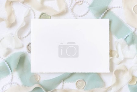 Photo for Card near  light green and beige silk ribbons and decor on white table top view,  Wedding mockup. Romantic scene with horizontal blank card. Valentines, Spring or Mothers day stationery - Royalty Free Image