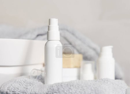 Photo for White blank spray bottle on light grey folded towel near basin in bathroom close up, cosmetic mockup. Modern lifestile scene with female personal care product - Royalty Free Image