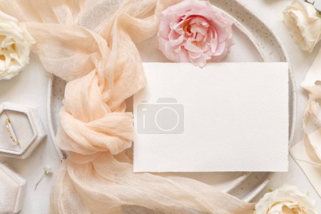 Photo for Horizontal Card near cream tulle fabric knot on plates top view near engagement ring in a velvet box, copy space. Wedding stationery mockup. Romantic table place with a blank menu card - Royalty Free Image