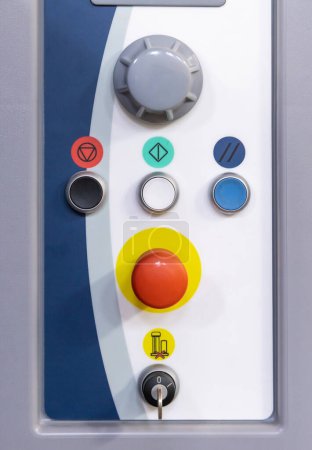 Téléchargez les photos : Panneau de commande gris avec gros bouton rouge et autres boutons et interrupteurs pour le fonctionnement des machines en production. Il a des symboles colorés. Ce système maintient la qualité et la cohérence dans la fabrication - en image libre de droit