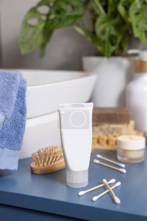 Photo for White cream tube on blue bathroom countertop near basin close up, packaging mockup, copy space. Natural personal care cosmetics and products - Royalty Free Image
