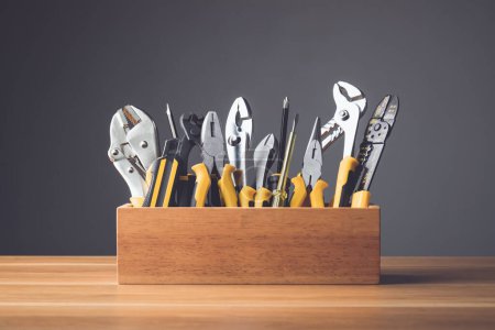 Téléchargez les photos : Ensemble d'outils pour le concept de réparation. Plusieurs outils en métal jaune kit pour le travail autonome dans une boîte en bois mis sur un bureau en bois avec fond mural gris. - en image libre de droit