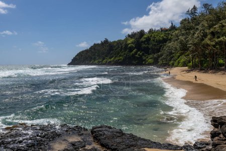 Téléchargez les photos : Paysage de la baie et de la colline verte Kahili Beach également connu sous le nom de Rock Quarry Beach avec des hommes pêchant devant les falaises verdoyantes à Kilauea, Kauai, Hawaï, États-Unis. - en image libre de droit