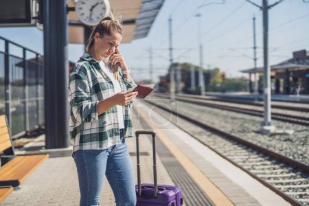 Téléchargez les photos : Femme confus regardant son billet alors qu'elle se tenait debout dans une gare. - en image libre de droit