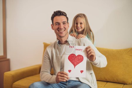Foto de Feliz padre e hija sosteniendo la tarjeta de felicitación con formas de corazón y texto. Concepto del día del padre. - Imagen libre de derechos