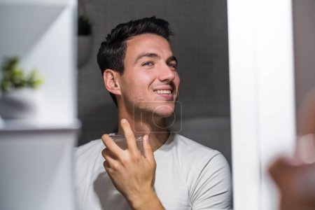 Téléchargez les photos : Man using perfume while looking himself in the mirror. - en image libre de droit