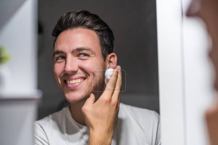 Téléchargez les photos : Man applying shaving cream while looking himself in the mirror. - en image libre de droit