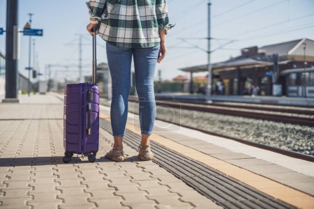 Foto de Mujer con maleta de pie en la estación de tren. - Imagen libre de derechos