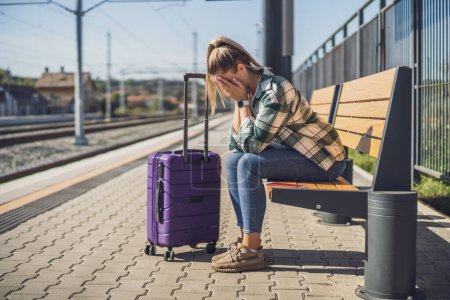 Photo for Worried woman sitting on a bench at the  train station. - Royalty Free Image
