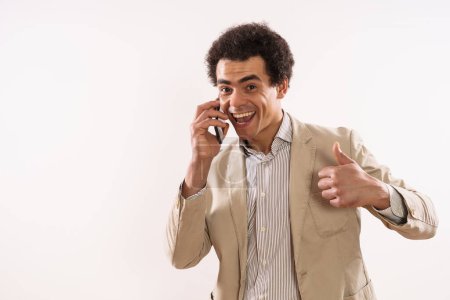 Téléchargez les photos : Image of happy businessman talking on the phone and showing thumb up. - en image libre de droit