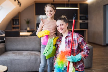 Téléchargez les photos : Mère heureuse et fille nettoyage maison ensemble. - en image libre de droit