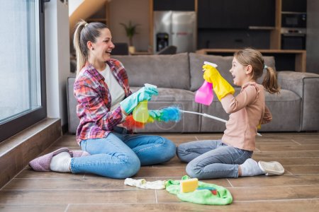 Photo for Happy mother and daughter having fun while cleaning  house together. - Royalty Free Image