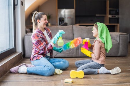 Foto de Feliz madre e hija divirtiéndose mientras limpian la casa juntas. - Imagen libre de derechos