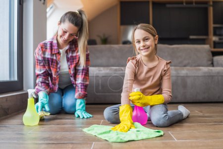 Téléchargez les photos : Fille heureuse et mère nettoyage maison ensemble. - en image libre de droit