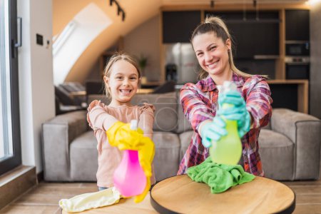 Foto de Feliz madre e hija divirtiéndose mientras limpian la casa juntas. - Imagen libre de derechos