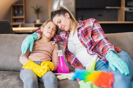 Photo for Happy mother and daughter resting after cleaning their house together. - Royalty Free Image