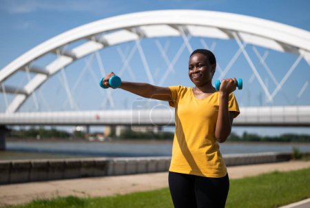 Téléchargez les photos : Jeune femme aime l'exercice avec des poids en plein air. - en image libre de droit