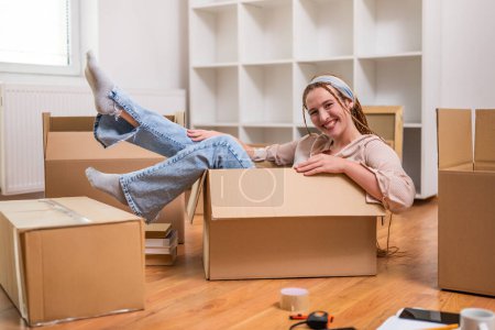 Téléchargez les photos : Femme heureuse s'amuser tout en déménageant dans un nouvel appartement
. - en image libre de droit