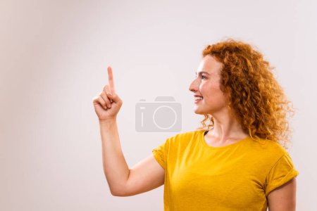 Foto de Retrato de hermosa mujer de jengibre apuntando sobre fondo gris. - Imagen libre de derechos