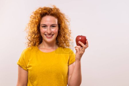 Foto de Retrato de mujer jengibre feliz sosteniendo manzana sobre fondo gris. - Imagen libre de derechos