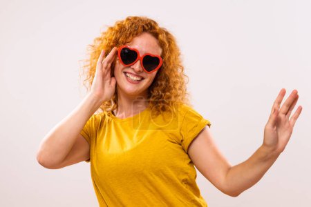 Téléchargez les photos : Image de femme gingembre heureux avec des lunettes de soleil en forme de coeur rouge. - en image libre de droit
