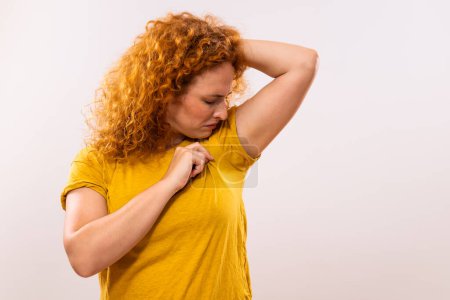 Foto de Mujer pelirroja está sudando mucho y no le gusta su olor debajo de la axila. - Imagen libre de derechos