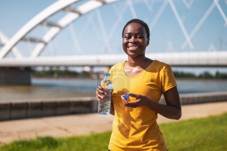Foto de Deportiva mujer bebiendo agua mientras hace ejercicio al aire libre. - Imagen libre de derechos