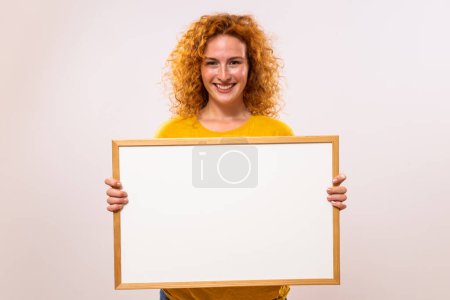 Foto de Hermosa mujer de jengibre está sosteniendo tablero blanco. - Imagen libre de derechos