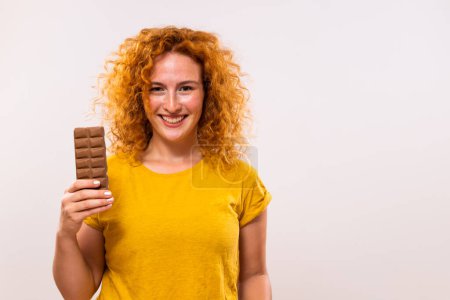 Photo for Portrait of happy cute ginger woman holding chocolate bar. - Royalty Free Image
