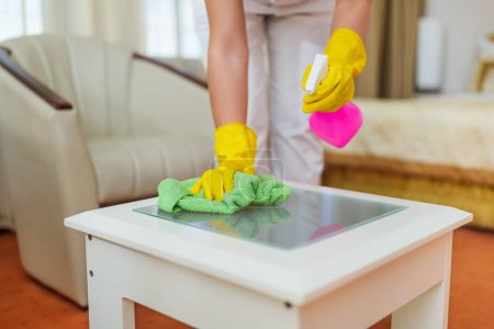 Photo for Close up image of  hotel maid cleaning table in a room. - Royalty Free Image