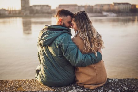 Photo for Happy couple embracing while  enjoy sitting by the river. - Royalty Free Image