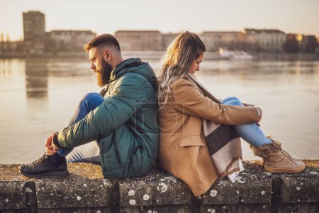 Téléchargez les photos : Couple ayant un conflit, homme et femme sont très en colère l'un sur l'autre tout en étant assis en plein air près de la rivière. - en image libre de droit