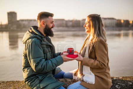 Photo for Man giving presents to his woman while they enjoy spending time together outdoor. - Royalty Free Image