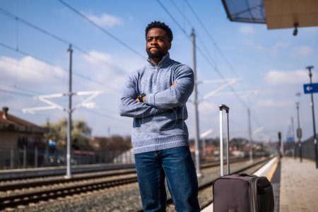Téléchargez les photos : Homme en colère avec une valise debout sur une gare. - en image libre de droit