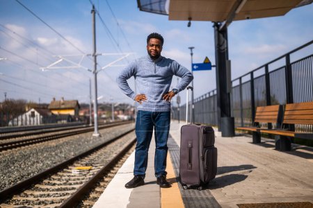 Photo for Worried man with a suitcase  standing on a railway  station. - Royalty Free Image