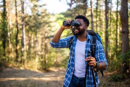 Photo for Young man enjoys using  binoculars and hiking  in nature. - Royalty Free Image