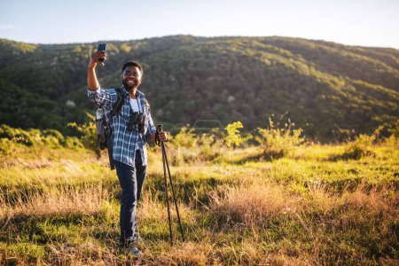 Téléchargez les photos : Jeune homme aime la randonnée et faire du selfie dans la nature. - en image libre de droit