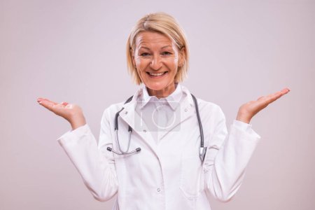 Photo for Portrait of mature female doctor gesturing on gray background. - Royalty Free Image