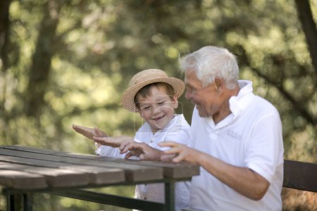 Foto de Happy senior man Grandfather with cute little boy grandson playing in forest - Imagen libre de derechos