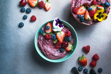 Photo for Two summer acai smoothie bowls with strawberries, blueberries,   on gray concrete background. Breakfast bowl with fruit and cereal, close-up, top view, healthy food - Royalty Free Image