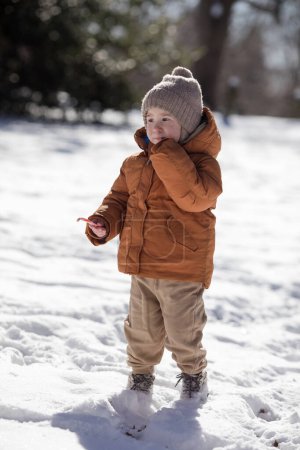 Portrait of two year old boy standing in fresh snow in winter playing outdoors